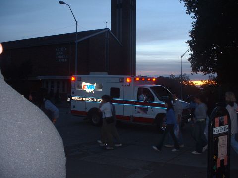1999 Ford Crown Victoria - An ambulance is parked outside a church as people gather around.