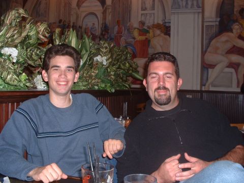 1999 Ford Crown Victoria - Two men are seated at a table in a restaurant, with decorative plants and artwork in the background.