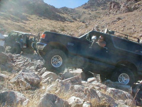 1988 Ford Bronco - A black 1987 Ford Bronco navigates a challenging rocky trail, with another vehicle visible behind it.
