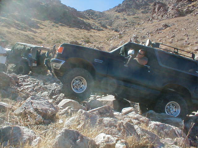 Black 1987 Ford Bronco climbing rocks