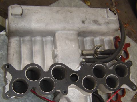 1993 Ford Bronco - Close-up view of an intake manifold with its associated gasket and fuel lines.