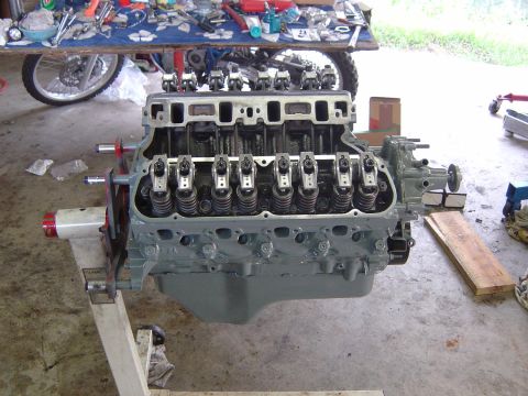 1993 Ford Bronco - Engine on a stand, ready for rebuild or installation. Tools and parts are scattered around the workspace.