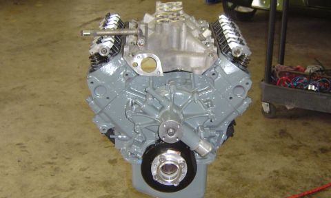1993 Ford Bronco - A gray V8 engine with aluminum intake and chrome valve covers sits on a shop floor next to a tool cart.