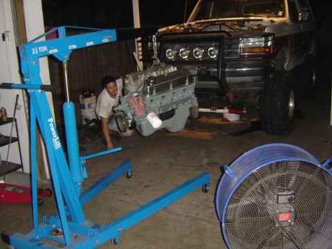1993 Ford Bronco - An engine is being removed from a truck using an engine hoist in a garage setting.