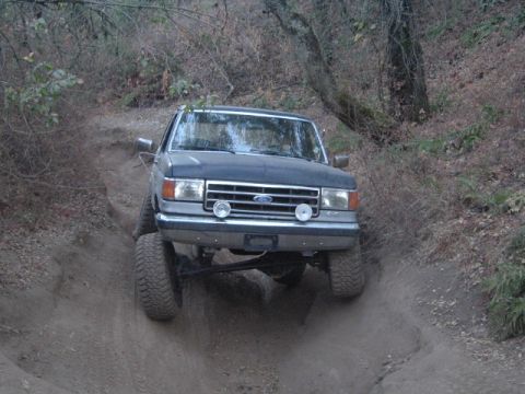 1989 Ford Bronco - This dark blue Ford F-Series truck navigates a steep dirt path, its off-road capabilities.