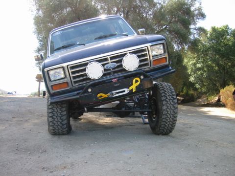 1985 Ford Bronco - This lifted 1980s Ford Bronco features a custom bumper with a winch and auxiliary lights, suggesting off-road use.