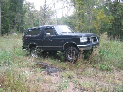 1988 Ford Bronco - This 1988 Ford Bronco is parked off-road in a wooded area with tall grass.