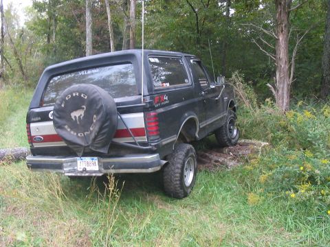 1988 Ford Bronco - This Ford Bronco is parked off-road, with its spare tire mounted on the rear door.