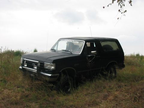 1988 Ford Bronco - A black Ford Bronco sits in a grassy field under an overcast sky.