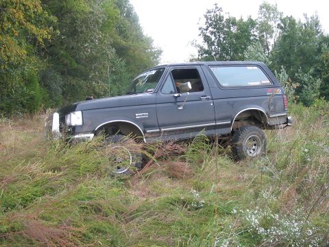 1988 Ford Bronco - This 1988 Ford Bronco is parked off-road in a grassy area with trees.