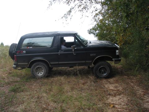 1988 Ford Bronco - This black 1988 Ford Bronco is seen off-roading, a spare tire mounted on the rear.