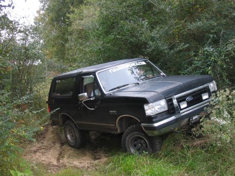 1988 Ford Bronco - This 1988 Ford Bronco navigates a dirt path surrounded by lush green foliage.