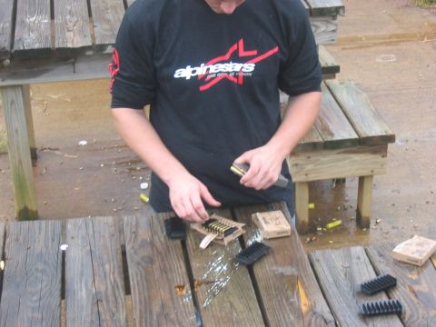 1988 Ford Bronco - A person is shown cleaning firearm components on a wet wooden table outdoors.