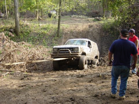 1983 Ford Bronco - This SUV is stuck in the mud and being pulled by a strap, with two men observing the scene.