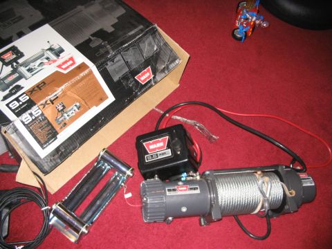 1986 Ford Bronco - A Warn 9.5 XP winch and its components are displayed on a red surface, with the product box in the background.