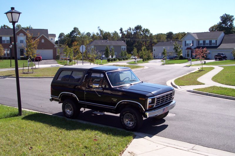 Black Ford Bronco parked on suburban street. Front grille and headlights visible