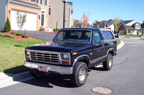 1983 Ford Bronco - A black 1983 Ford Bronco is parked on a suburban street on a sunny day.