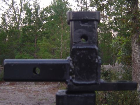 1993 Ford Bronco - A trailer hitch receiver is shown in detail against a backdrop of trees and a fence.