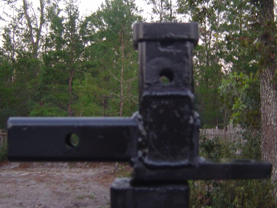 Close-up of a black trailer hitch receiver with a hole in the side