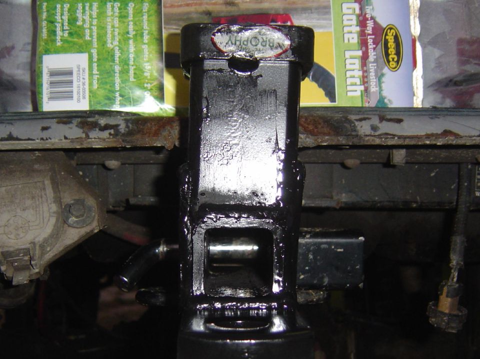 Black trailer hitch receiver with a "Trophy" sticker, showing internal mechanism
