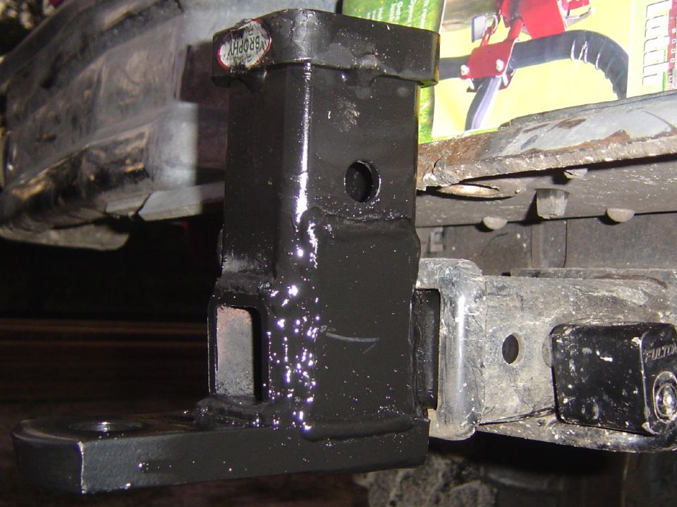Hitch receiver with a trailer hitch attached. Text 'FULTON' visible on hitch