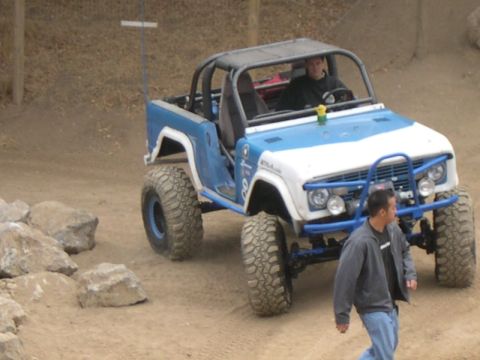 1990 Ford Bronco - An off-road vehicle with a blue and white paint scheme and a roll cage is seen on a dirt track.