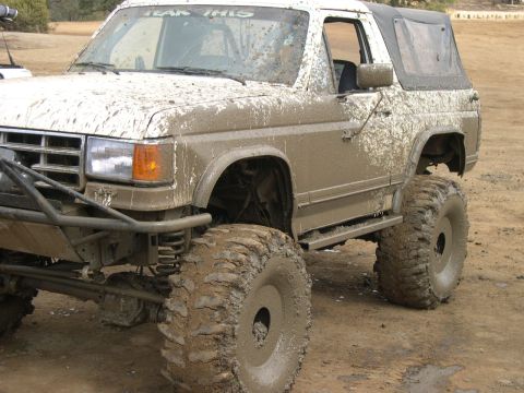 1990 Ford Bronco - This heavily modified SUV is covered in mud, suggesting recent off-road use.