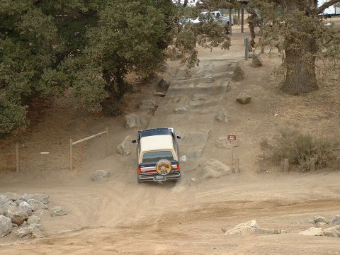 1990 Ford Bronco - This Ford Bronco is navigating an off-road course with a dirt ramp and rocks.