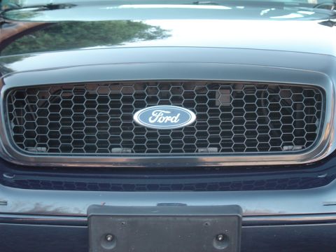 1999 Ford Crown Victoria - The honeycomb grille and Ford oval badge are visible on this dark blue vehicle.