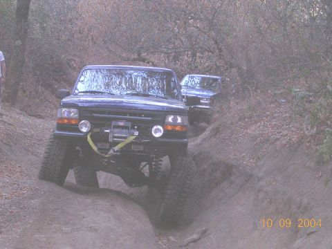 1994 Ford Bronco - Two Ford Broncos navigate a steep dirt trail during an off-road excursion.