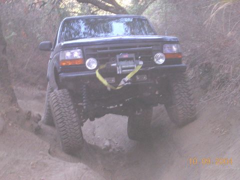 1994 Ford Bronco - A black Ford Bronco navigates a dusty trail with its front wheels angled.