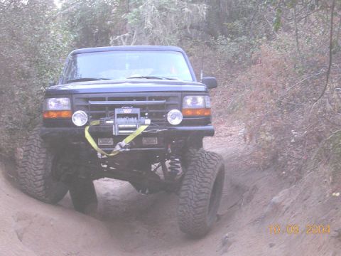 1994 Ford Bronco - This 1994 Ford Bronco is equipped with a winch and large off-road tires, navigating a dirt trail.