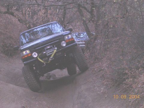 1994 Ford Bronco - 1994 Ford Bronco navigating an off-road trail with a second vehicle in the background.
