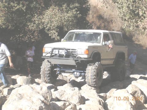 1994 Ford Bronco - Modified white SUV navigates a rocky trail on a sunny day.