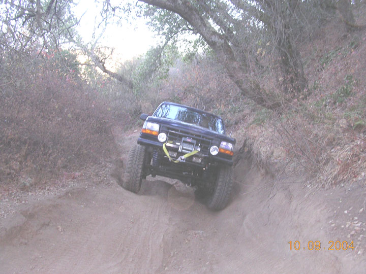 Black off-road truck with winch going down a steep dirt path. Date stamp reads 10.09.2004