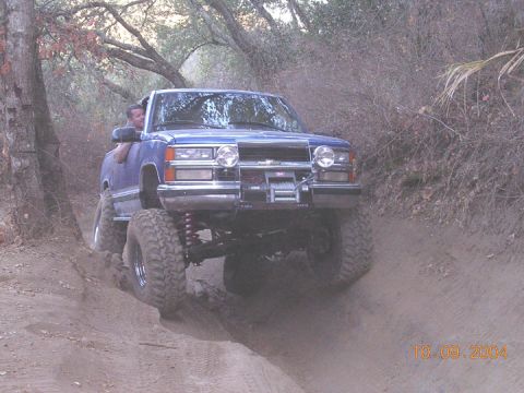 1994 Ford Bronco - A blue pickup truck navigates a dirt path with a driver visible.