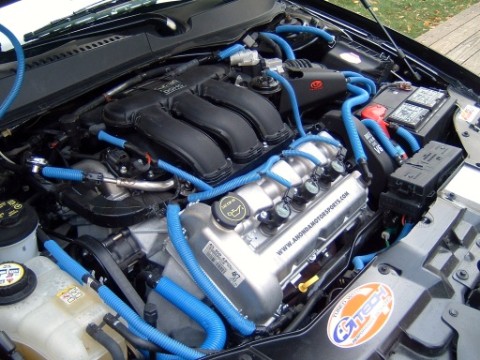 2004 Ford Taurus - The engine bay is filled with blue hoses and custom wiring, with visible text on the engine cover.