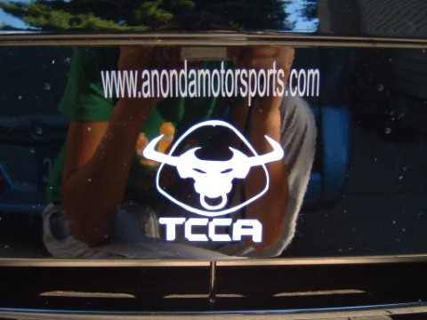 2004 Ford Taurus - A sticker with a bull logo and website is affixed to the rear of a dark-colored vehicle.