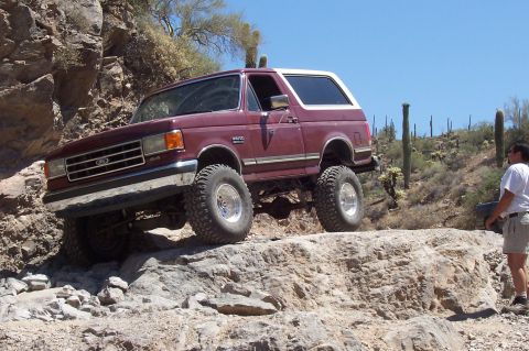 1992 Ford Bronco - This 1992 Ford Bronco navigates a challenging rocky trail under a clear blue sky.