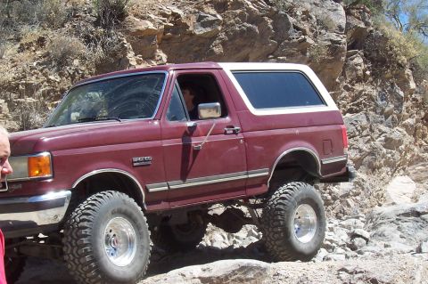 1992 Ford Bronco - 1992 Ford Bronco tackling a challenging off-road course in a desert environment.