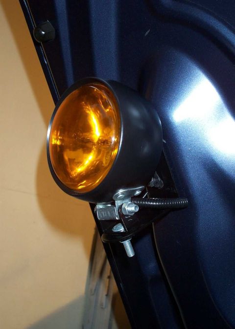 1998 Ford Crown Victoria - Close-up of an aftermarket amber fog light installed on a dark blue vehicle's exterior.