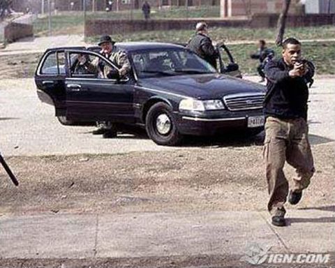 1991 Ford LTD Crown Victoria - A dark sedan with its doors open is parked on a street, with people around it.