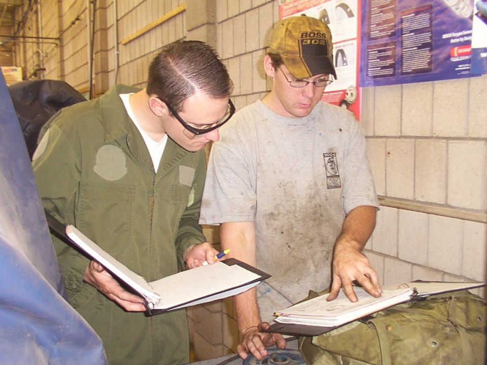 Two men in a workshop review documents