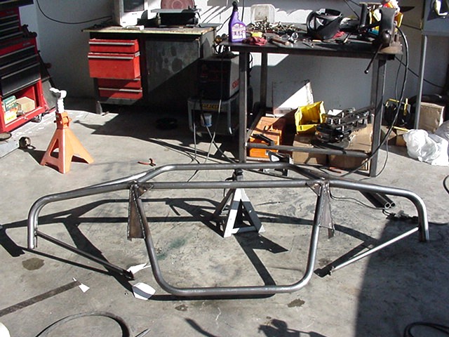 Bare metal tubular chassis or cage fabrication on jack stands in a workshop