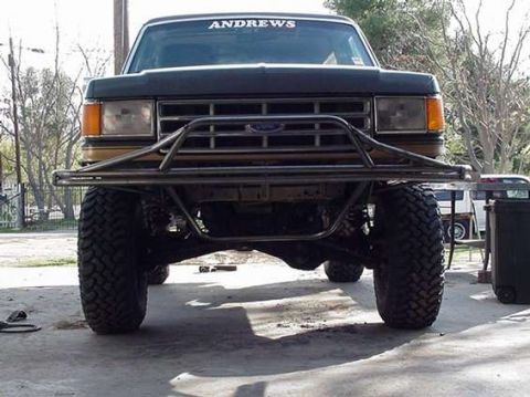 1990 Ford Bronco - Front view of a black lifted Ford truck on a concrete floor showing a tubular prerunner-style bumper and an ANDREWS windshield banner.