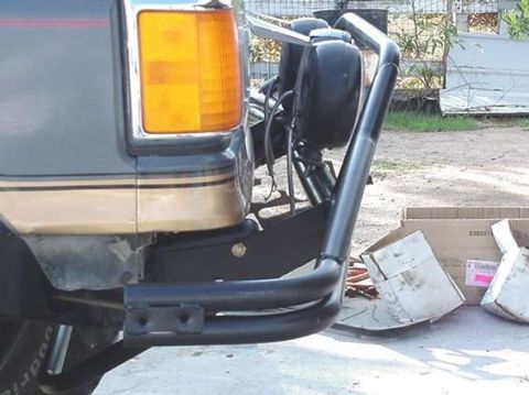 1990 Ford Bronco - Close-up of a black tubular front bumper and amber turn signal on the corner of an SUV.