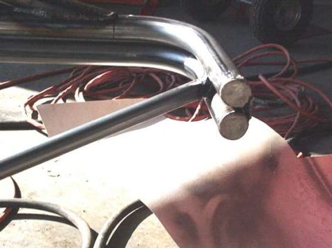 1990 Ford Bronco - freshly welded tubular steel joint sits on red fender sheet metal amid wiring during fabrication.