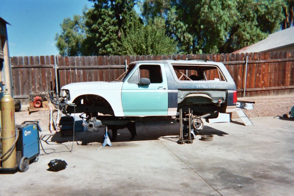 Stripped SUV body shell on stands in a backyard during a build