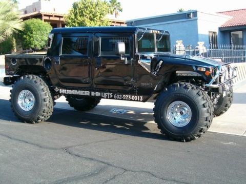 1982 Ford Bronco - This black Hummer H1 features oversized tires and "HUMMER H1 LIFTS" branding on its side.