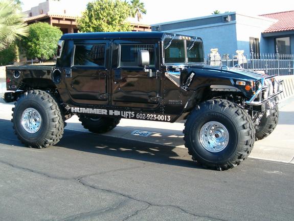 Black Hummer H1 with large tires and "HUMMER H1 LIFTS" text on the side